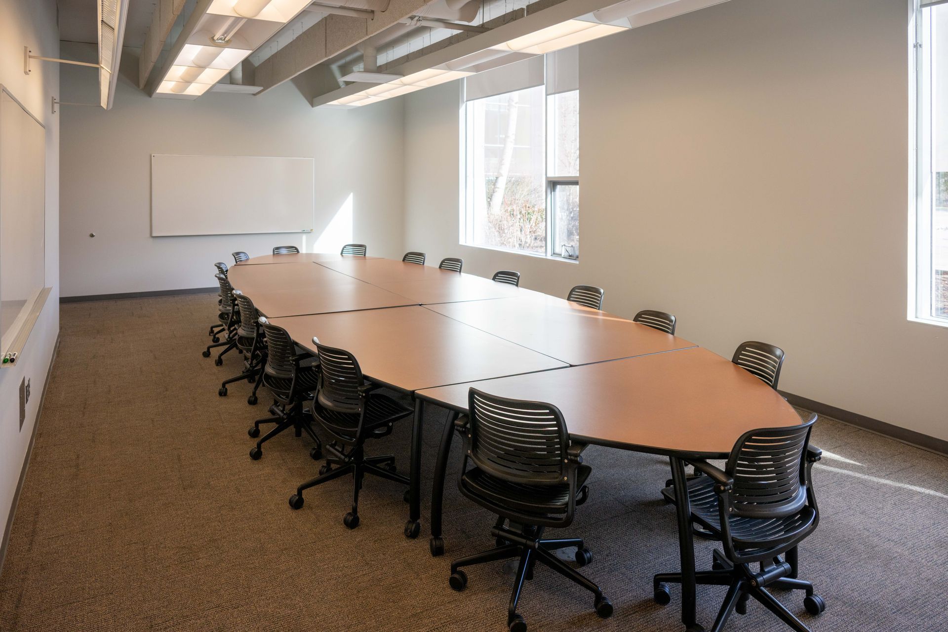 Conference room with long table, chairs, whiteboard, and windows.