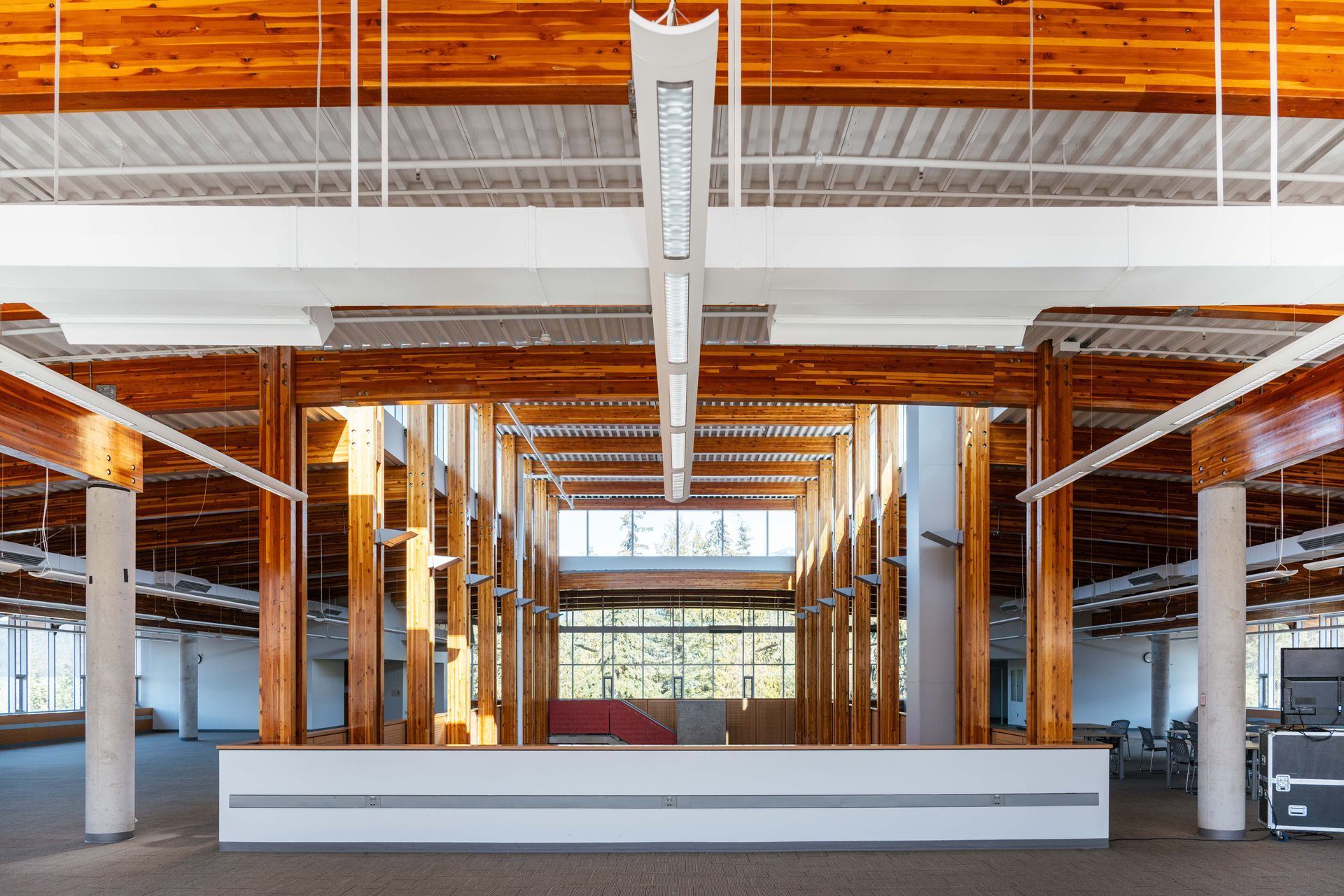 Modern empty office lobby with wood beams, white columns, and a long front desk