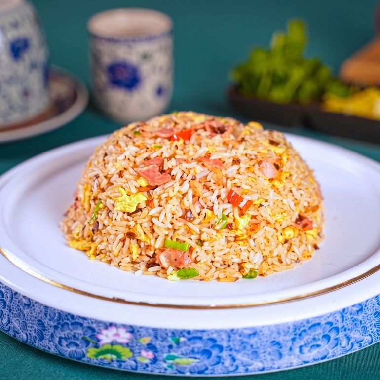 Plate of fried rice on a white dish, topped with green herbs, on a restaurant table