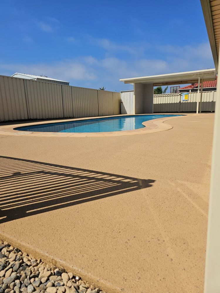 A Large Swimming Pool is Surrounded by a Fence on a Sunny Day — Mid North Coast Spray Pave in South West Rocks, NSW