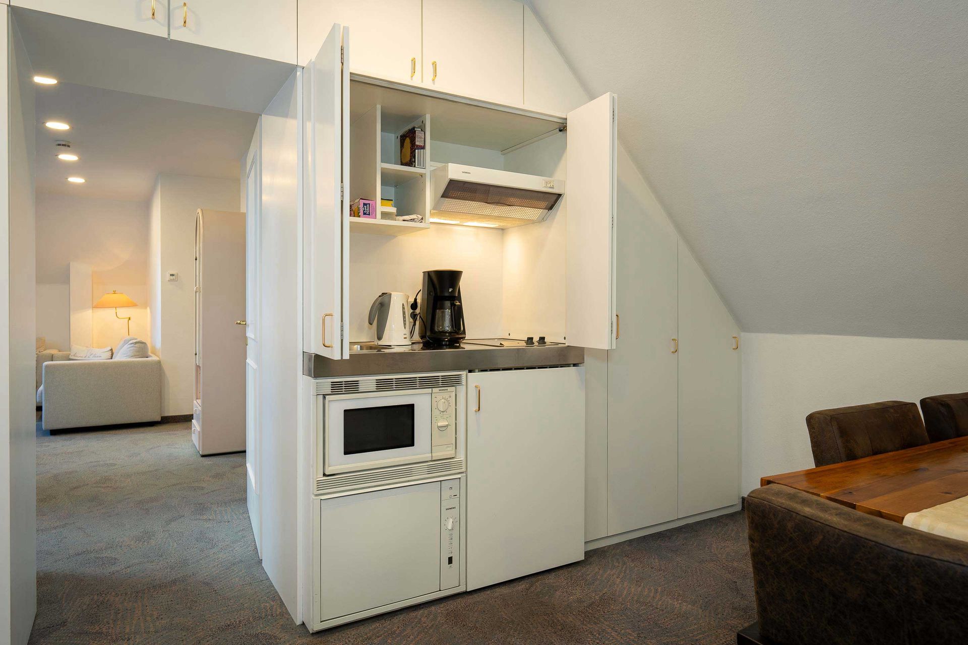 Eine kleine Küche mit Mikrowelle & Kühlschrank im Apartment des Boutique Hotel Rosengarten Hamburg in Poppenbüttel