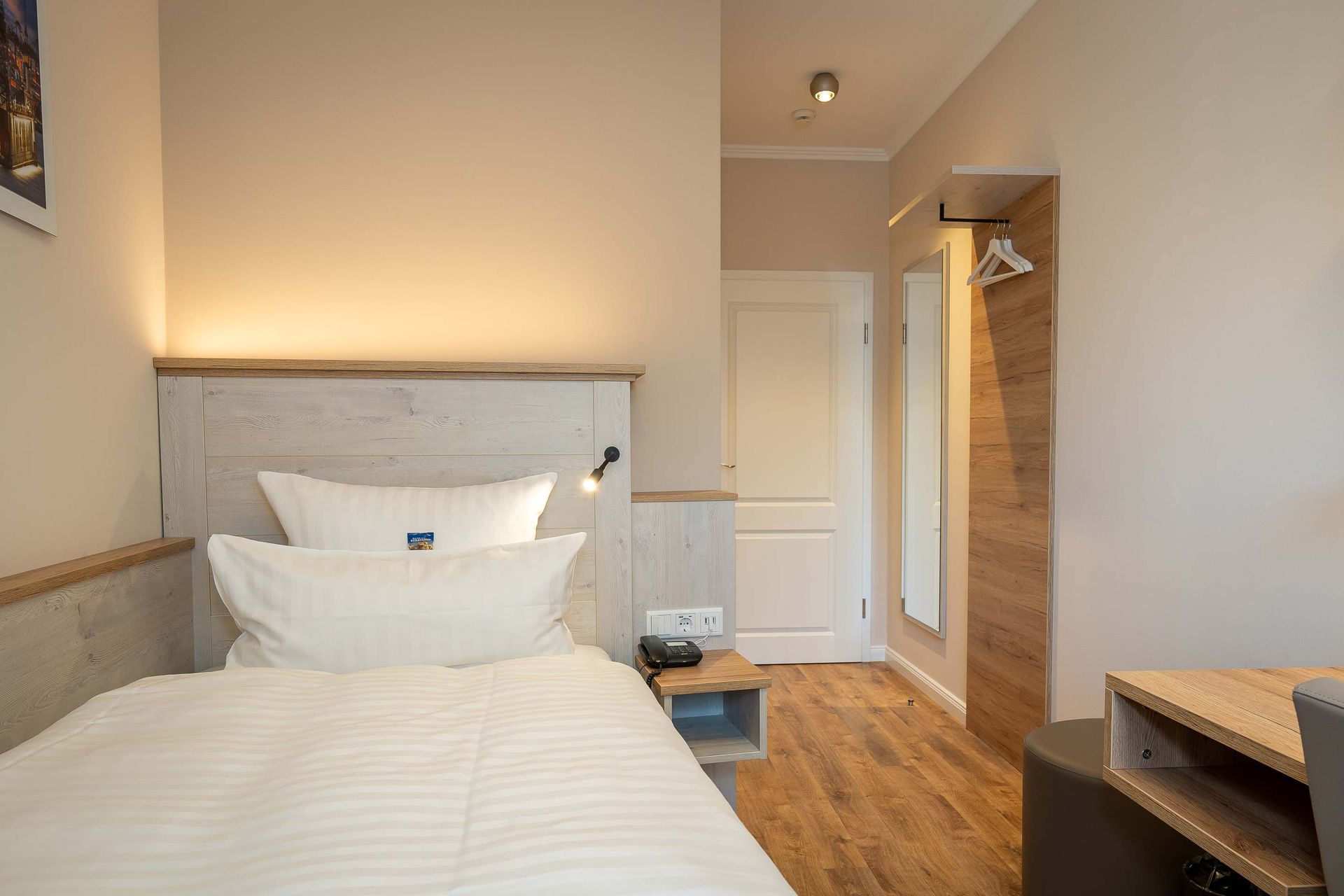 Ein Hotelzimmer mit einem Einzelbett und Holzboden.