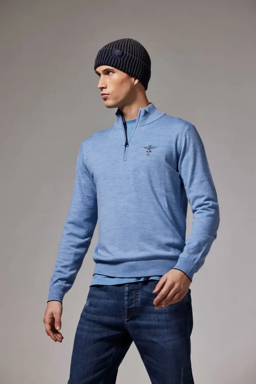 Manden har en blå sweater og en sort hue på.