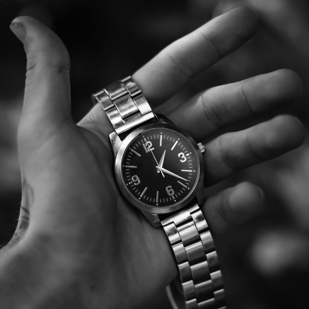 Silver watch with a black face and a metal band.