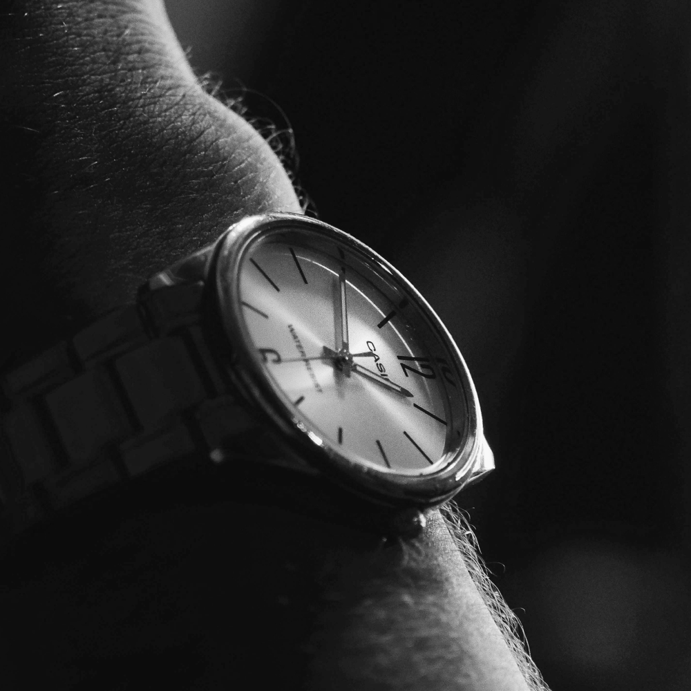 Black and silver wristwatch with black leather band on white background.