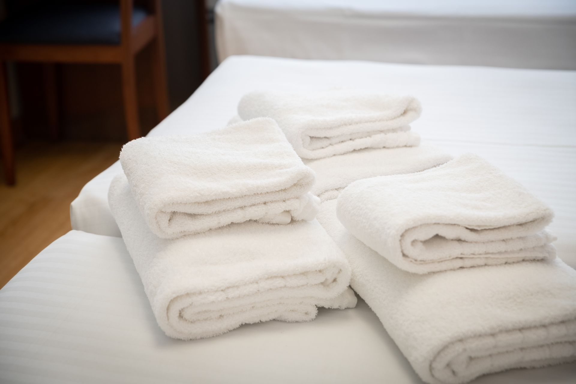 Toallas blancas dobladas y apiladas sobre una cama bien hecha en un dormitorio luminoso