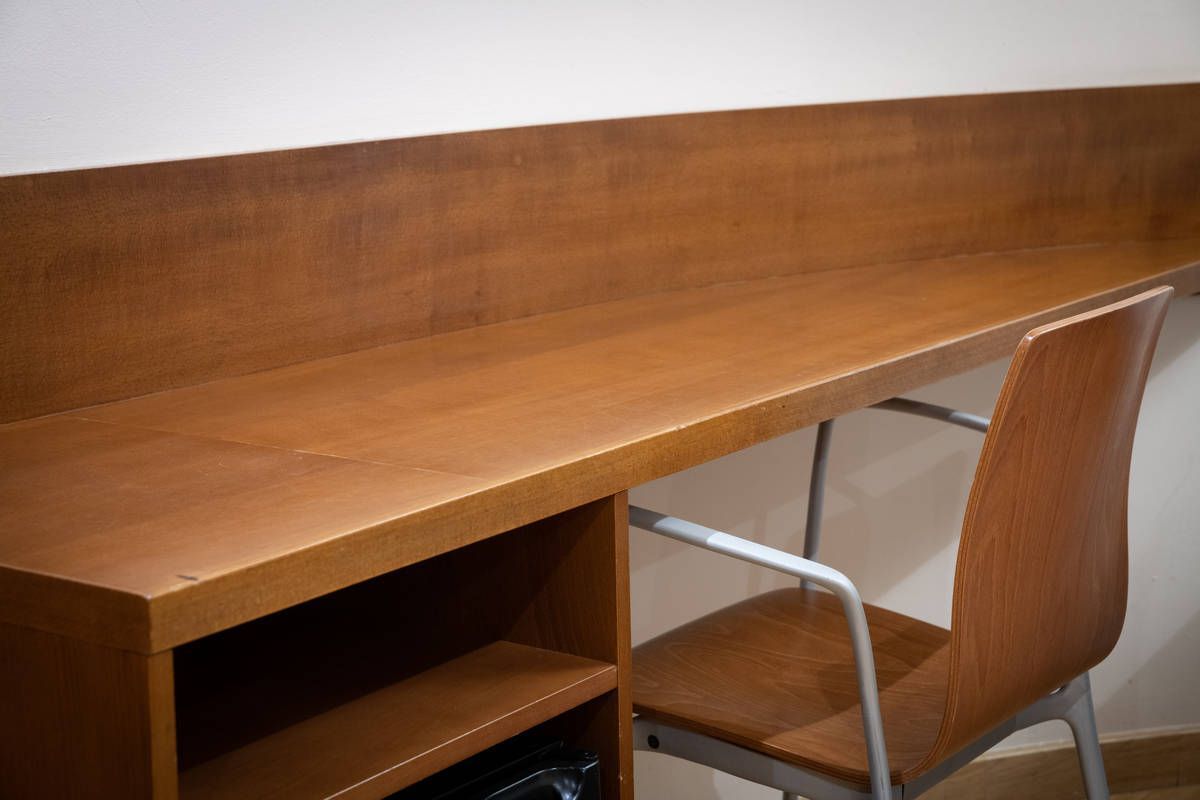 Escritorio de madera con estantes incorporados y una silla en un espacio de trabajo sencillo de oficina
