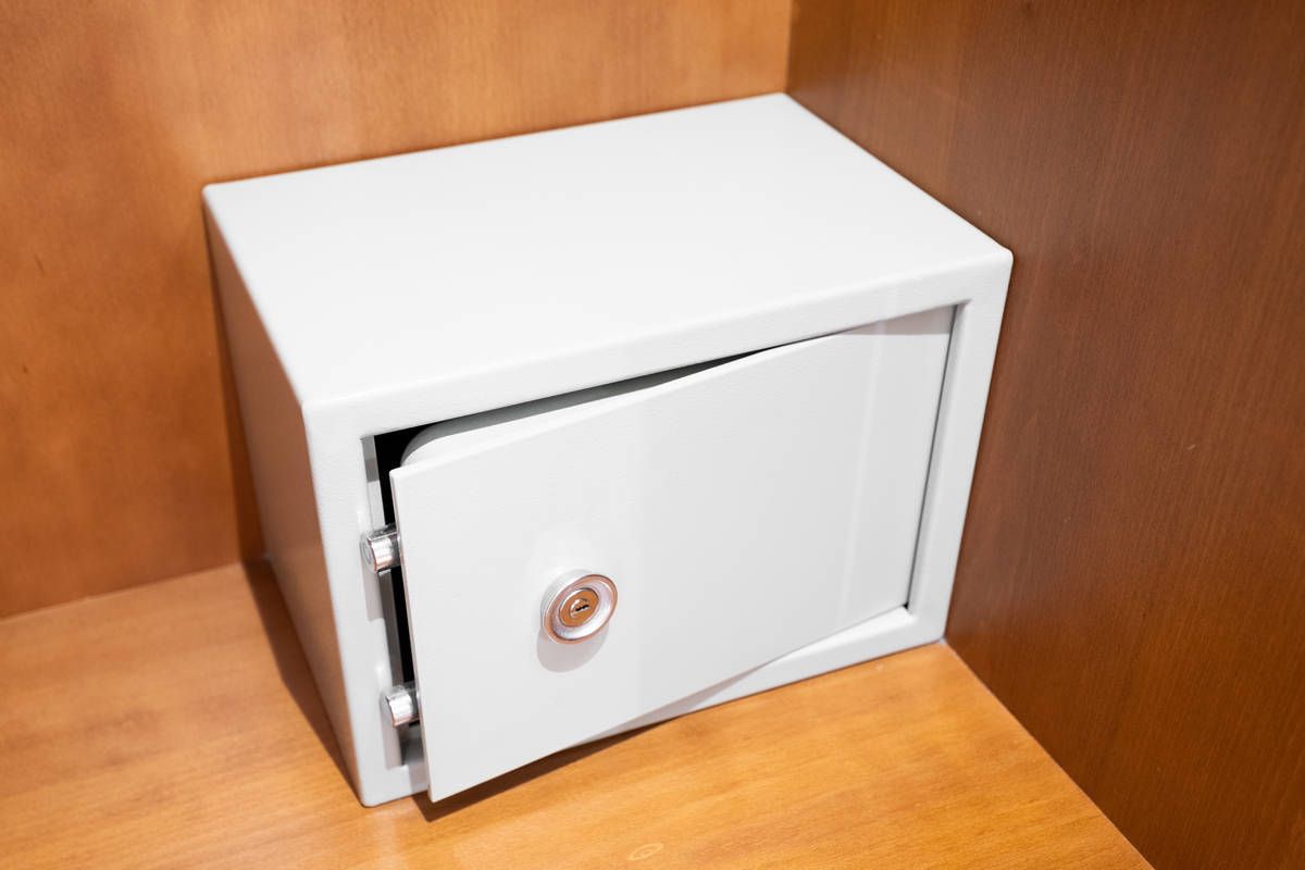 Pequeña caja fuerte blanca empotrada en un armario de madera, con la puerta ligeramente abierta.