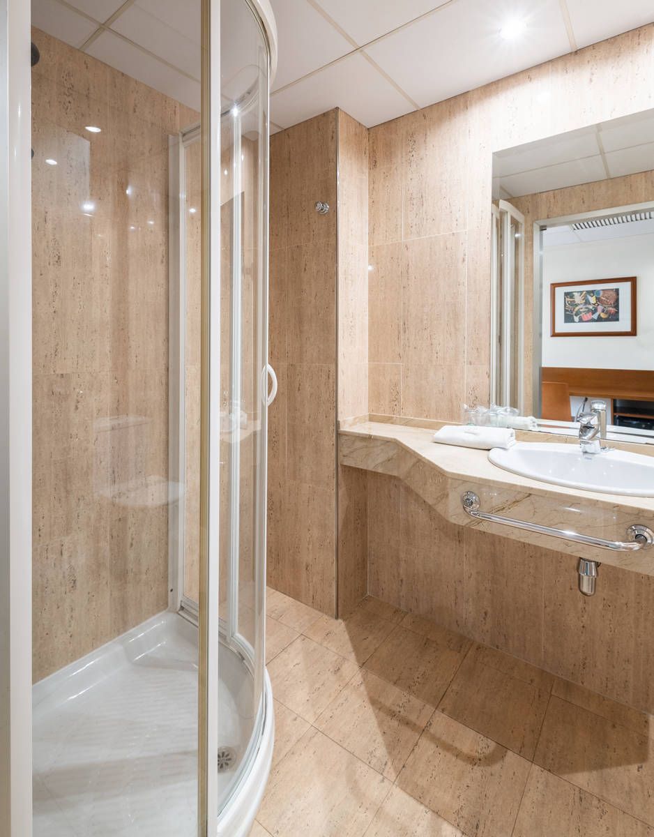 Baño moderno en tonos beige, con ducha de cristal y mueble de lavabo curvo