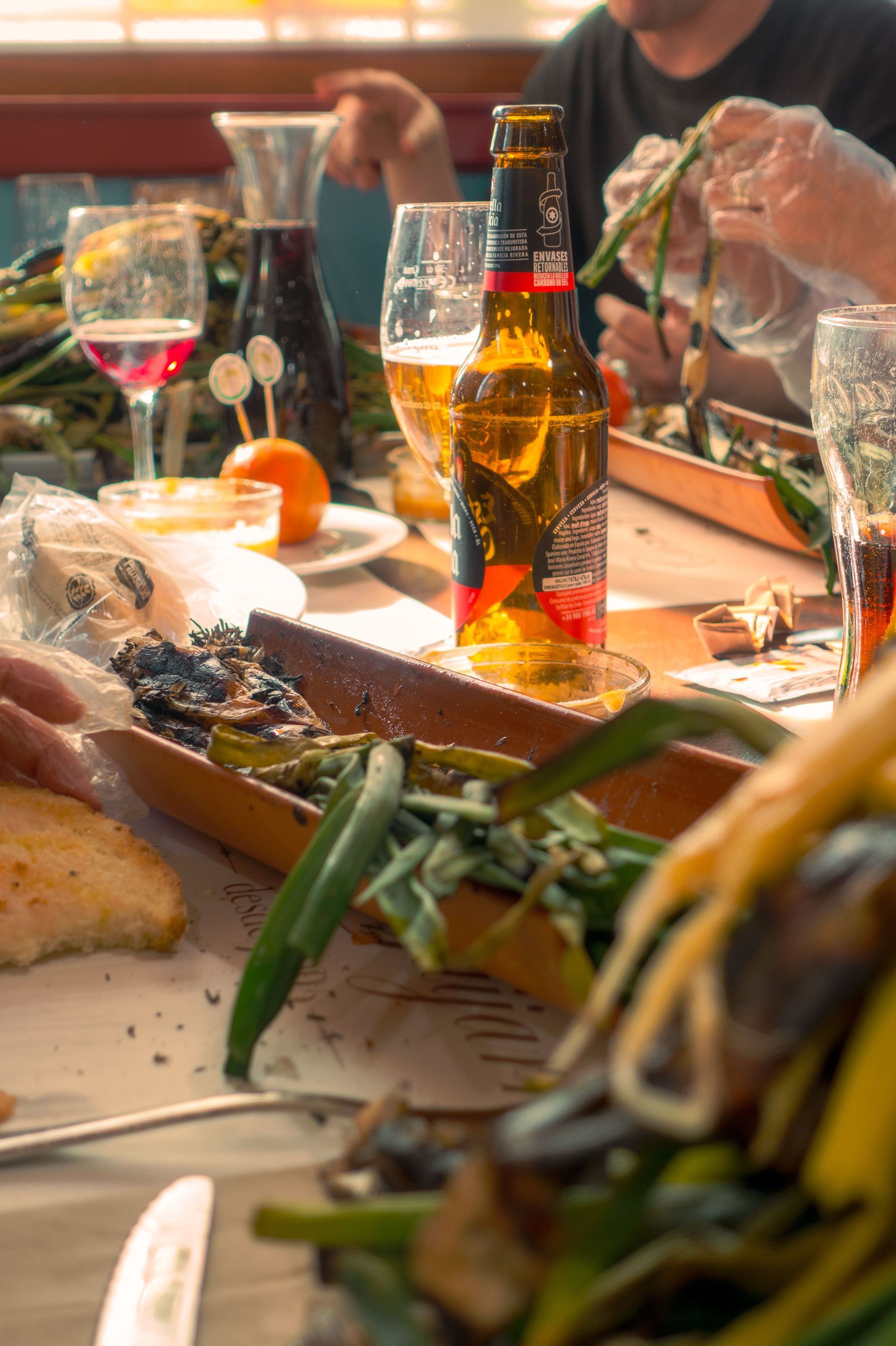 Mesa con varios platos y dos copas de vino tinto, en un ambiente cálido e informal.