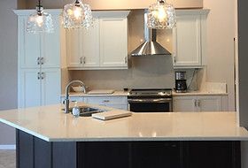 Modern kitchen with white cabinets, stainless steel appliances, and a quartz countertop island.