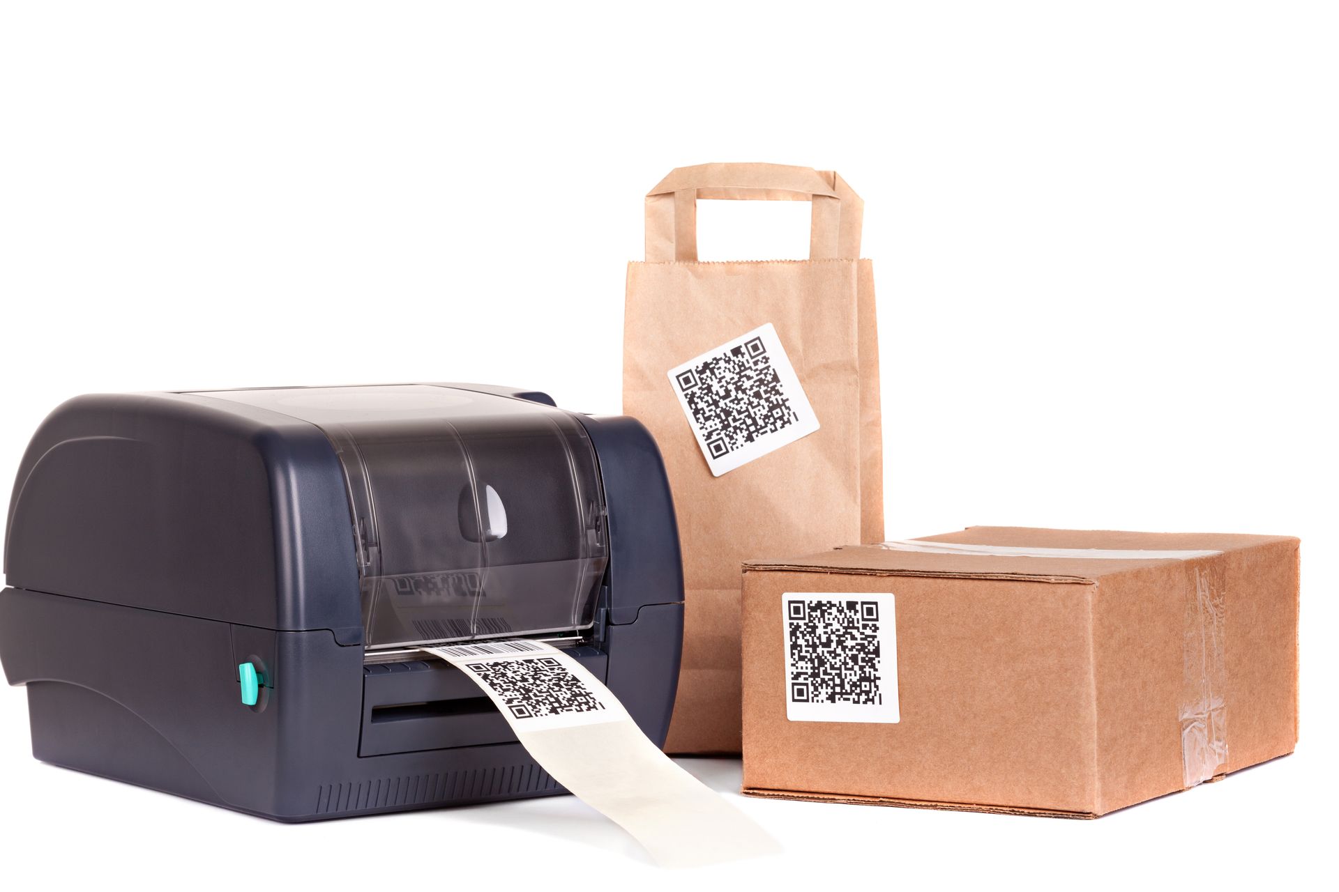 Une imprimante d'étiquettes de bureau imprime une étiquette à code QR à côté d'un sac en papier et d'une boîte en carton, tous deux munis d'étiquettes à code QR.