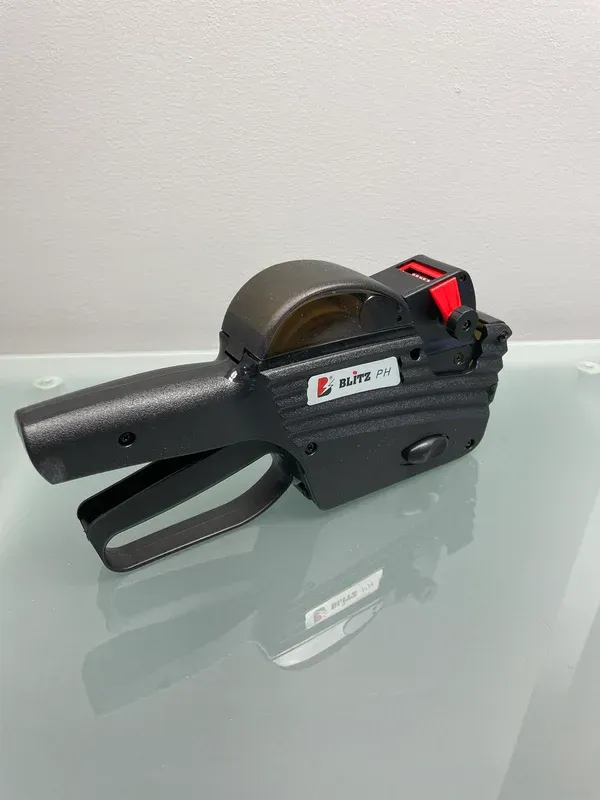 Étiqueteuse de prix noire avec détails rouges sur une surface réfléchissante.