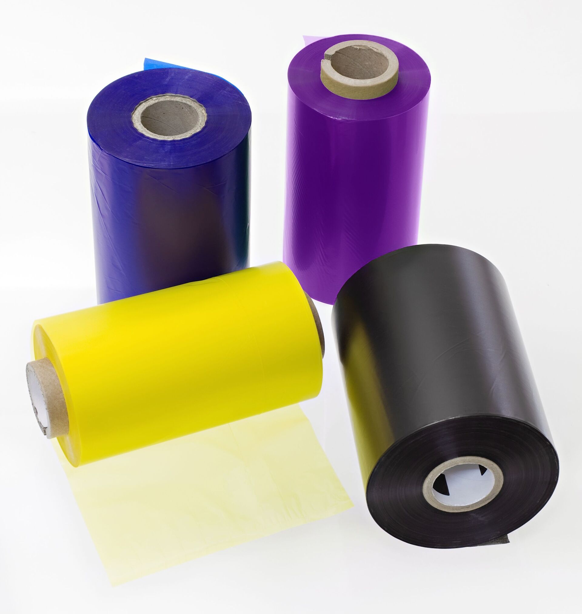 Quatre rouleaux de rubans de transfert thermique colorés : bleu, violet, jaune et noir.