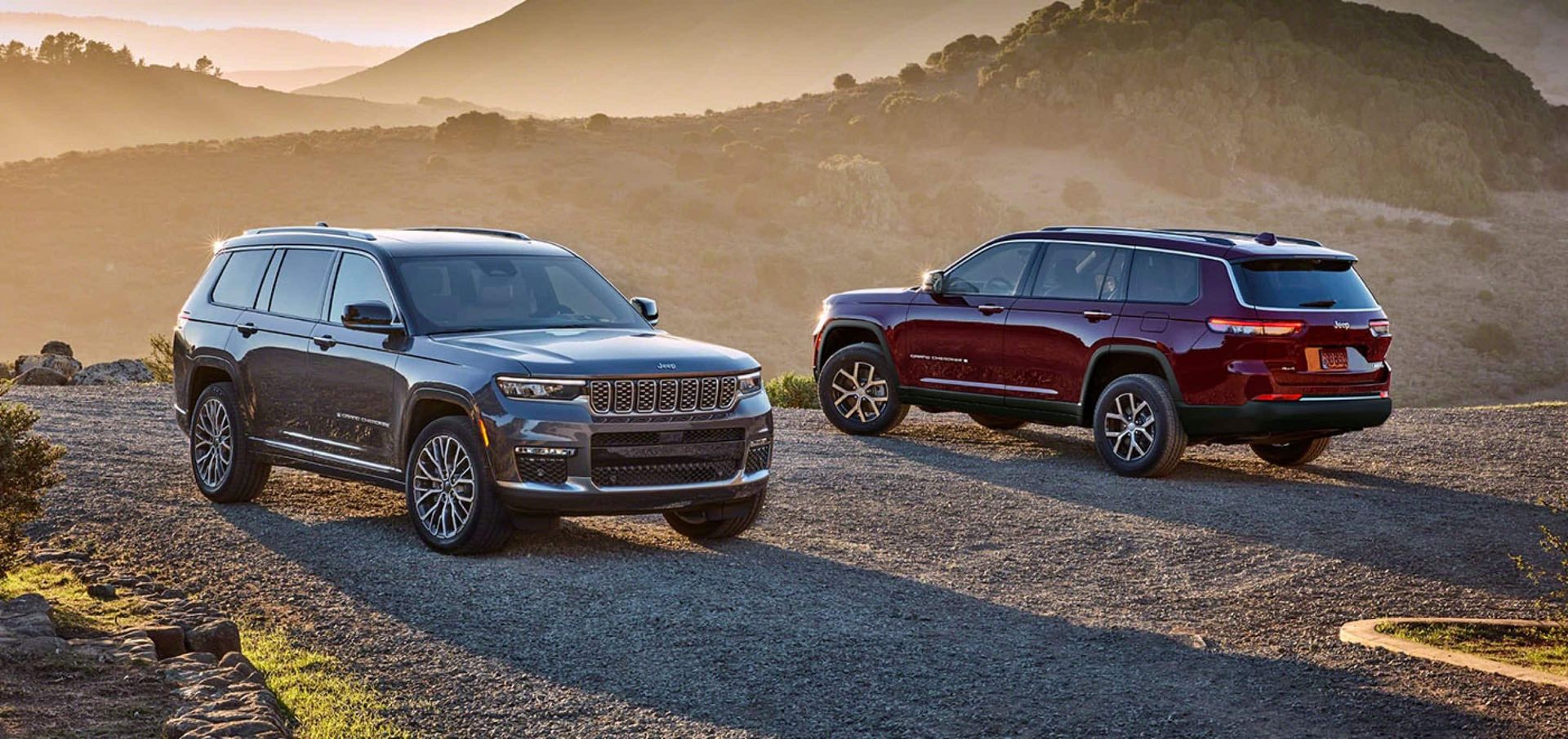 Two jeep grand cherokee are parked next to each other on a dirt road.