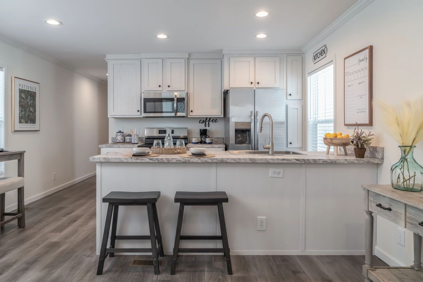 Kitchen with white cabinets, stainless steel appliances, breakfast bar, and two stools.
