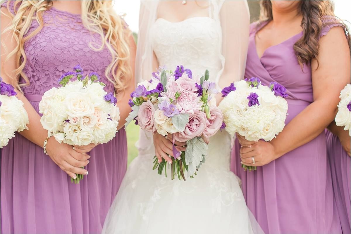 Bride and bridesmaids holding bouquets, wearing lavender dresses.