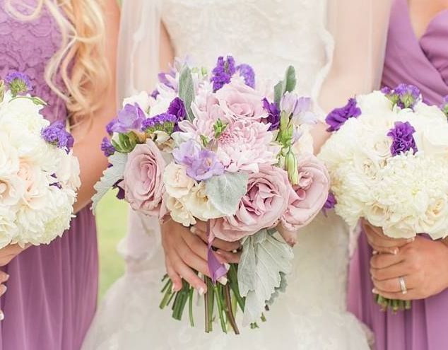 Bridesmaids in purple dresses holding bouquets with pink and purple flowers; wedding.