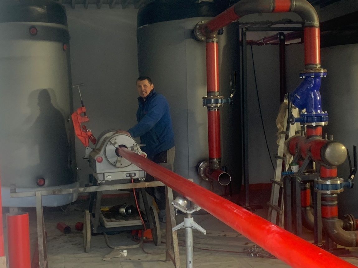 Operaio controlla l'installazione del riscaldamento a pavimento negli impianti industriali a Torino