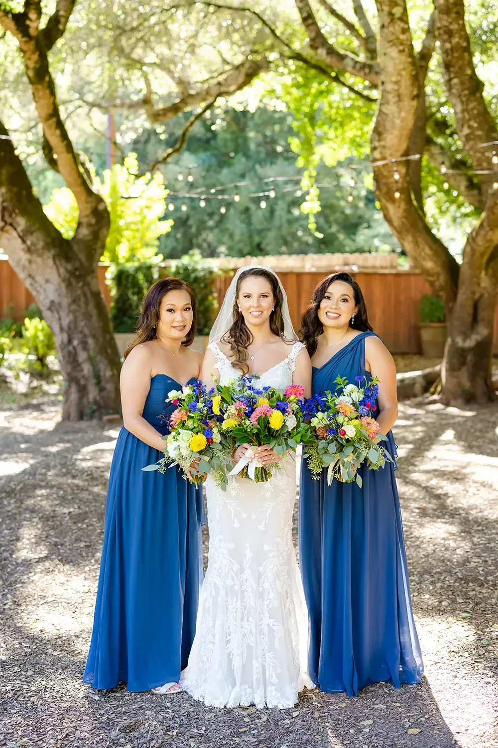 Bride and maids of honor in formal dresses holding bouquets of flowers