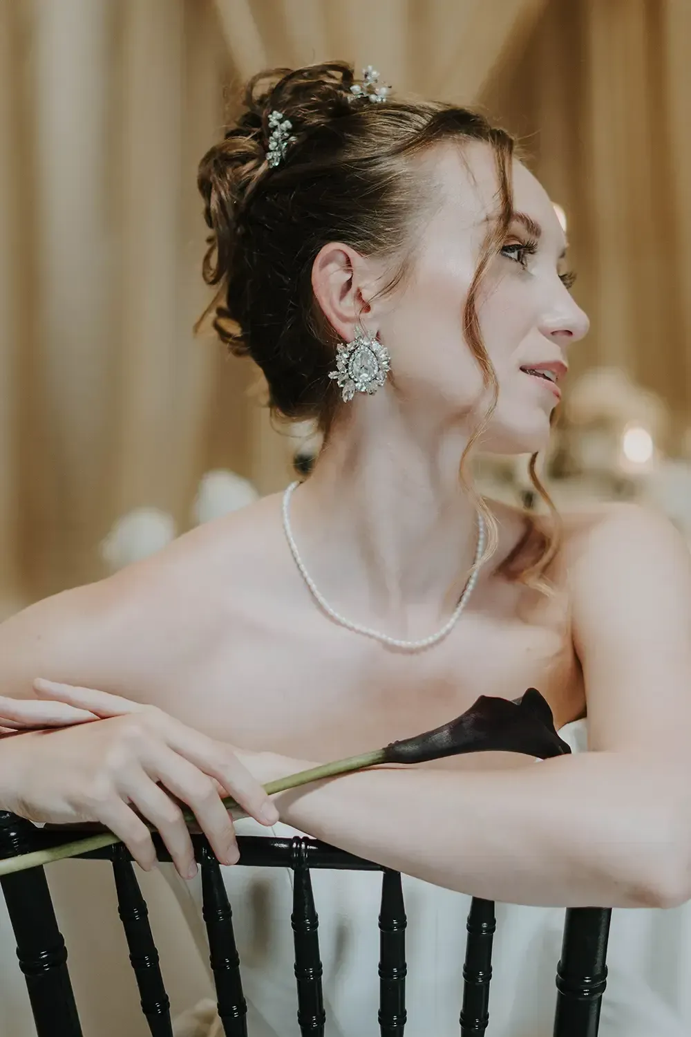 Elegant bride sitting in a chair holding a lily