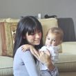 Woman holding a baby on a couch, both looking at the camera.