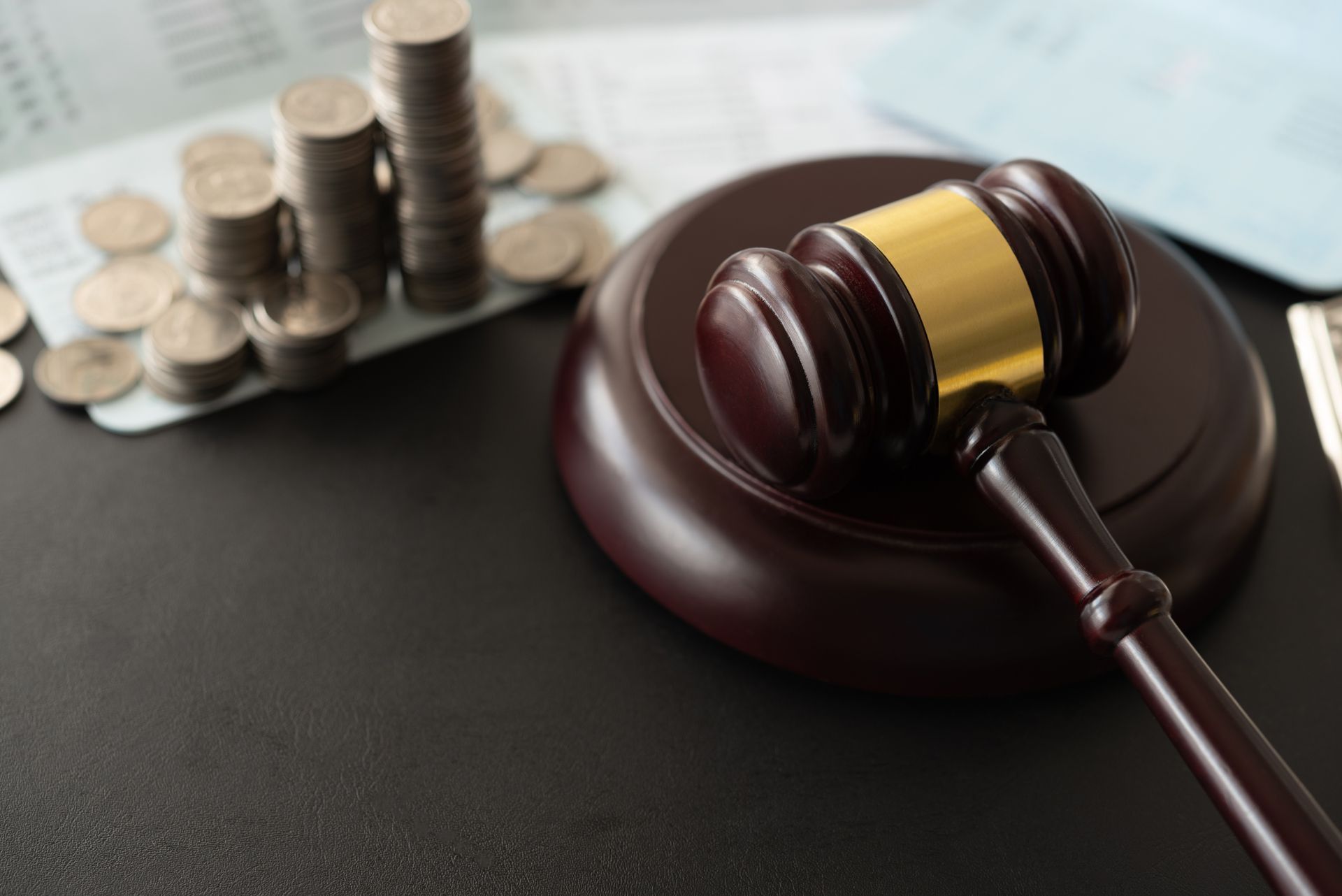 Judge’s gavel beside stacked coins and a calculator on a desk
