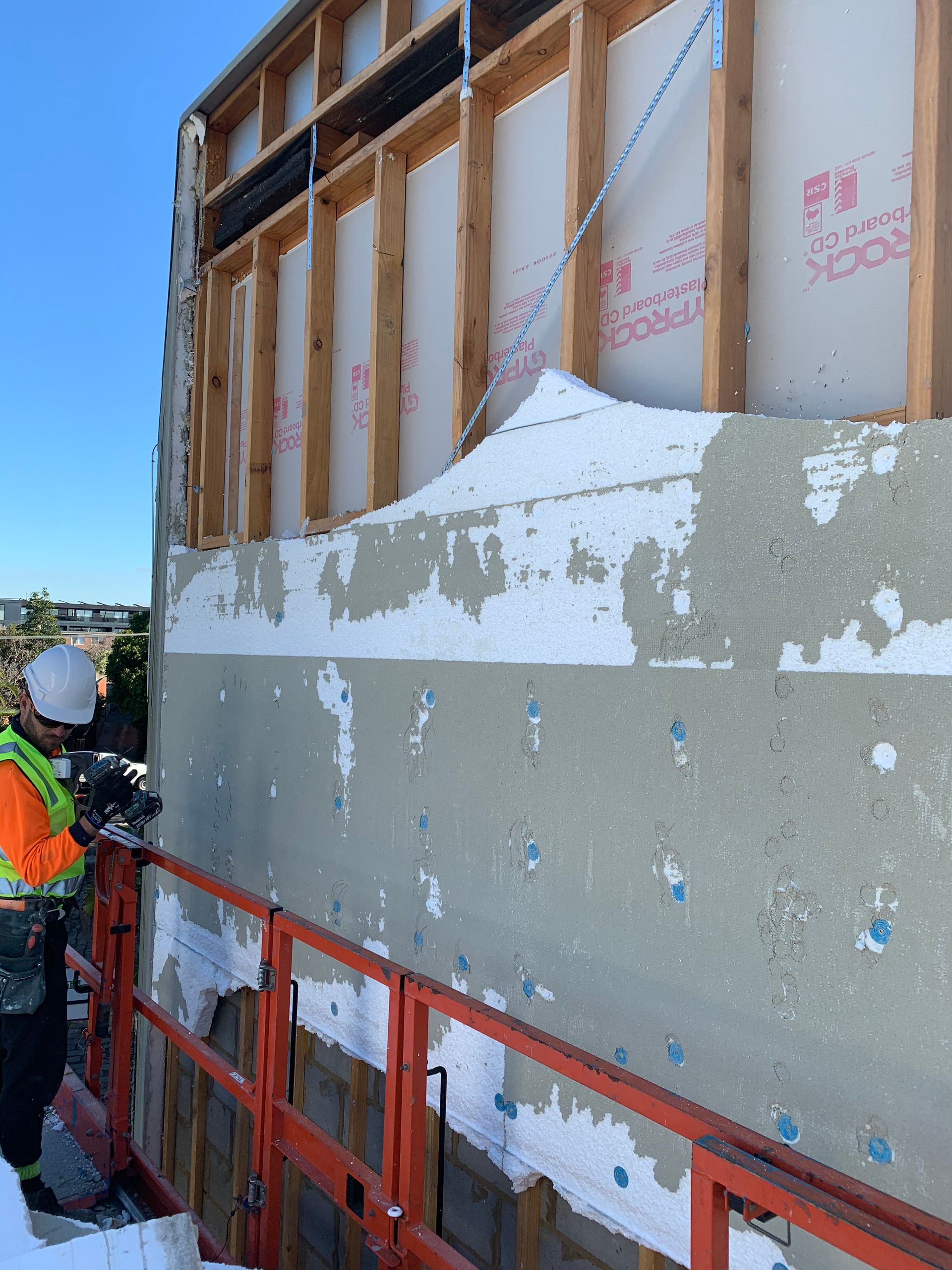 A man is working on a wall with scotch tape on it