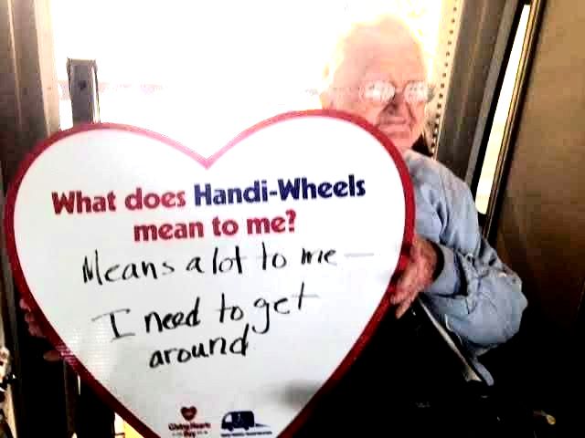 A female holding a heart with these written words: What does Handi-Wheels mean to me? Means a lot to me - I need to get around.