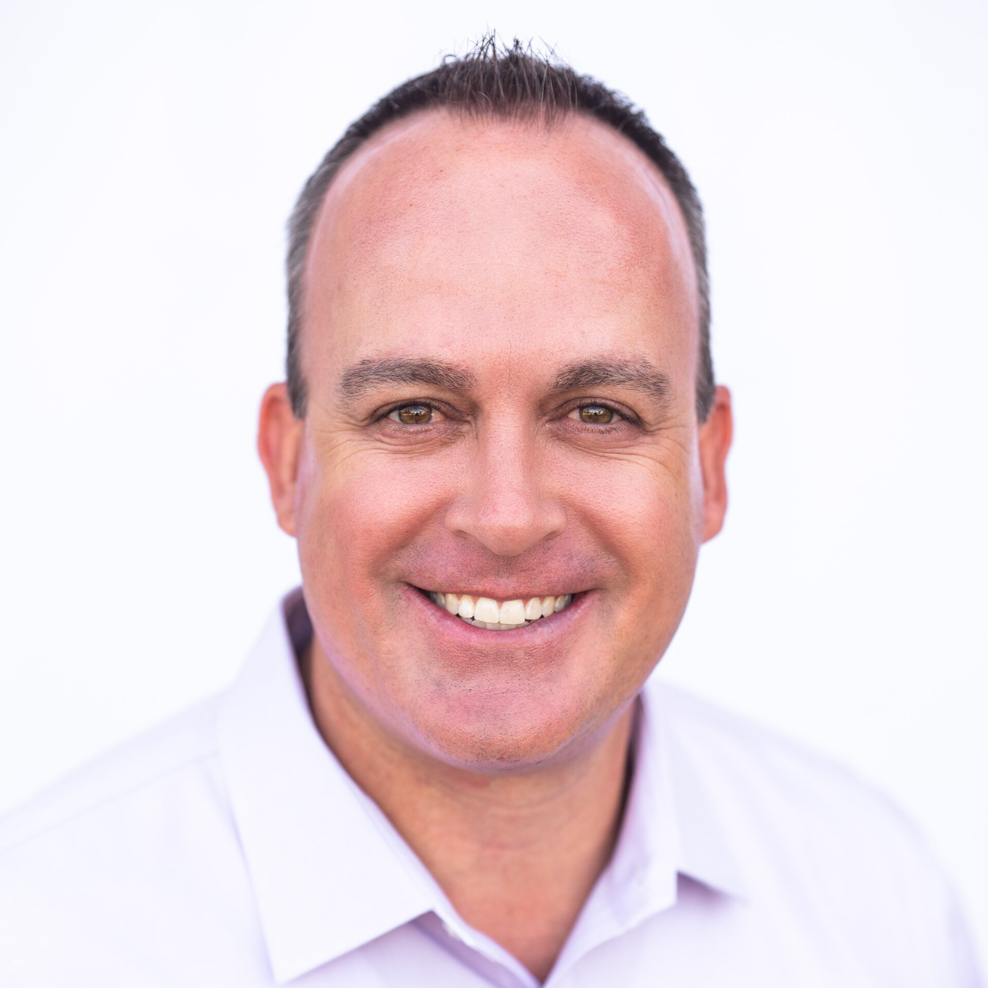 Smiling person in a white shirt against a plain white background