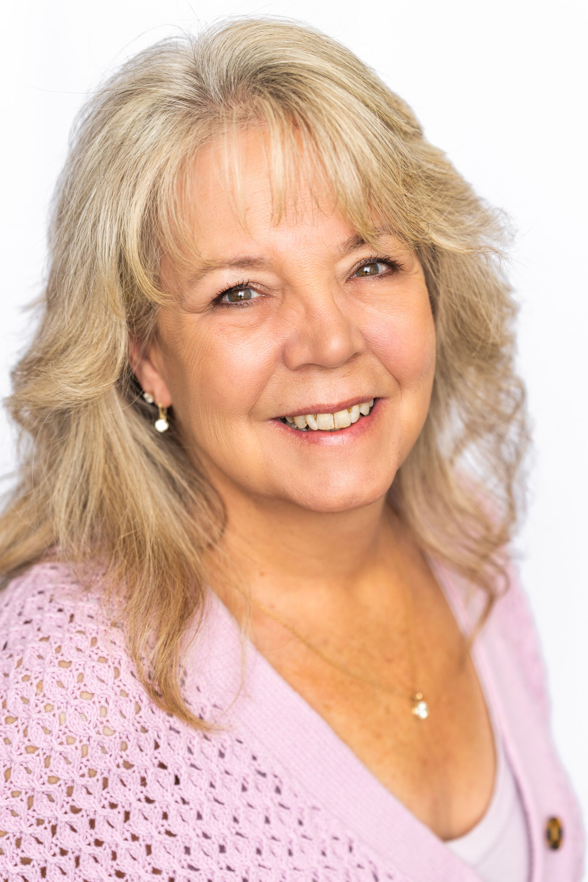 Smiling woman in a light pink cardigan against a white background