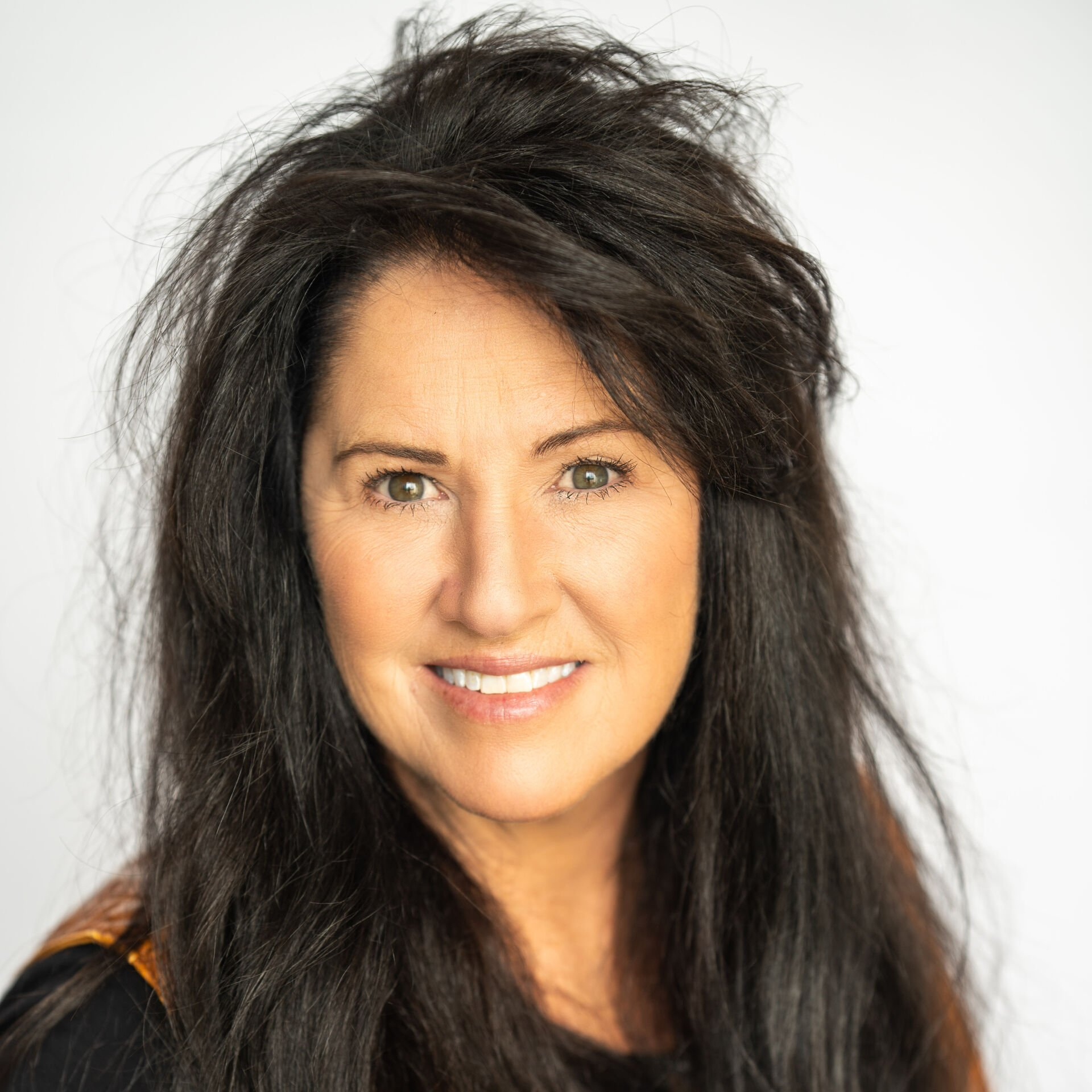 Portrait of a smiling woman with long dark hair against a light background