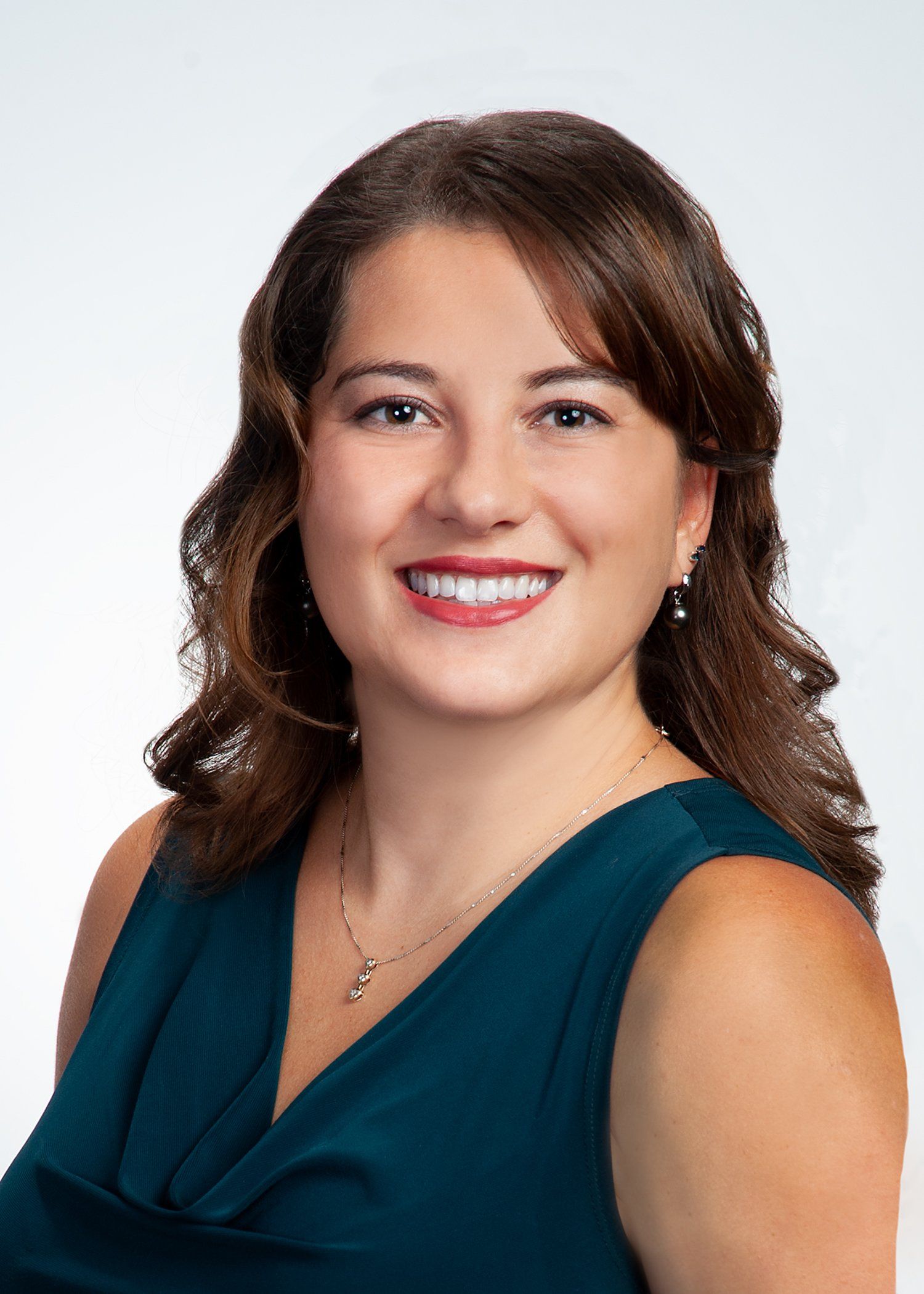 Studio headshot of a smiling person in a teal top against a white background