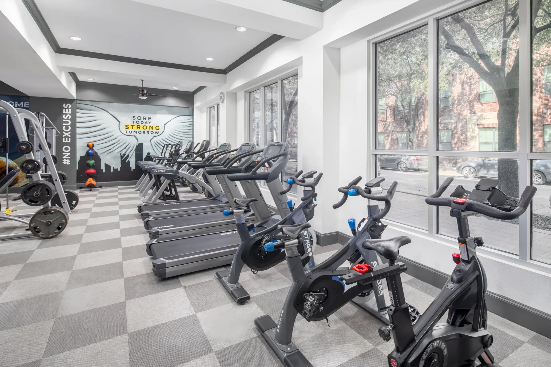 Well-equipped gym with cardio machines and a motivational wall mural at Marquis Enclave, offers apartments and lofts near HCC Central Campus.
