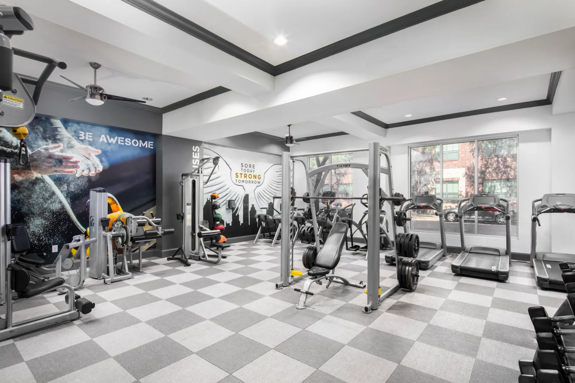 Interior view of a modern gym with exercise equipment and motivational wall art at Marquis Enclave, offers apartments and lofts near HCC Central Campus.
