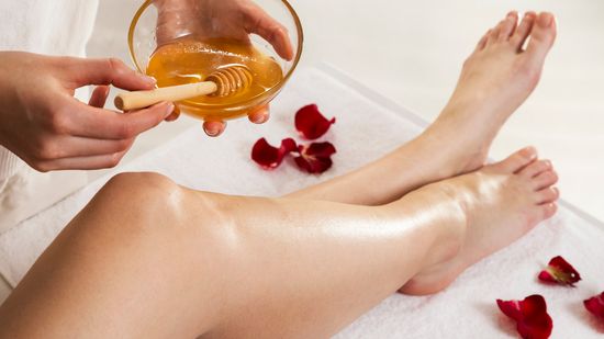 A woman is getting her legs waxed with honey.