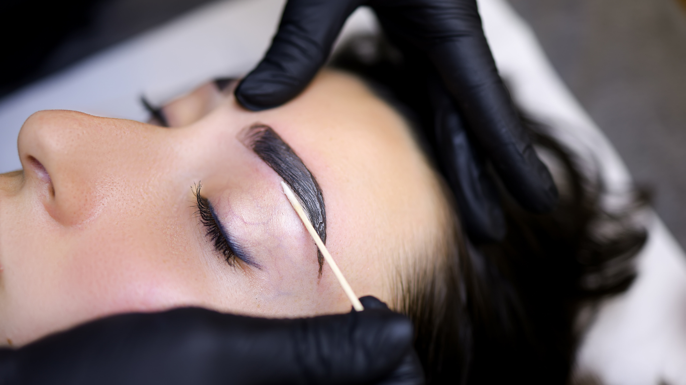 A woman is getting her eyebrows dyed in a salon.