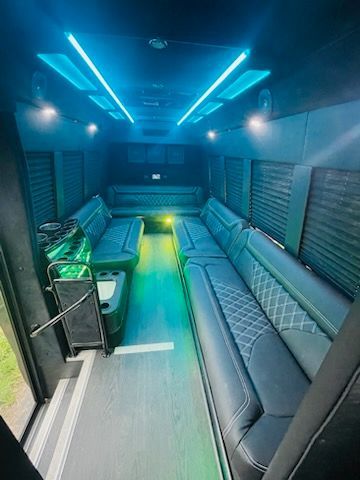 Blue-lit luxury van interior with quilted bench seating and green accent lights