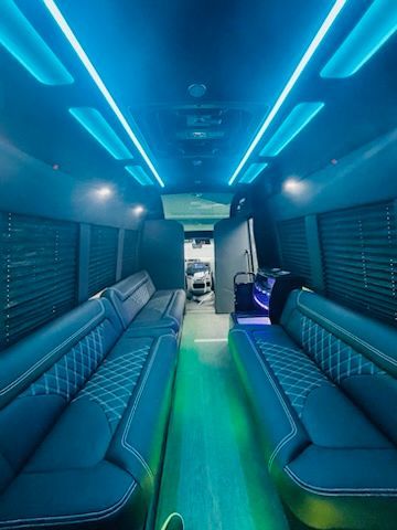 Blue-lit luxury van interior with turquoise bench seats and a glowing green floor strip