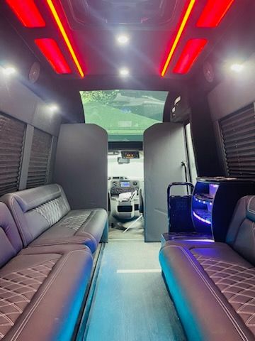 Luxury van interior with red ceiling lights, gray leather seats, and a front view of the driver’s area