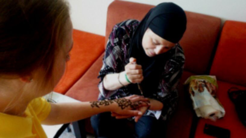 Een vrouw brengt henna aan op de arm van een andere vrouw