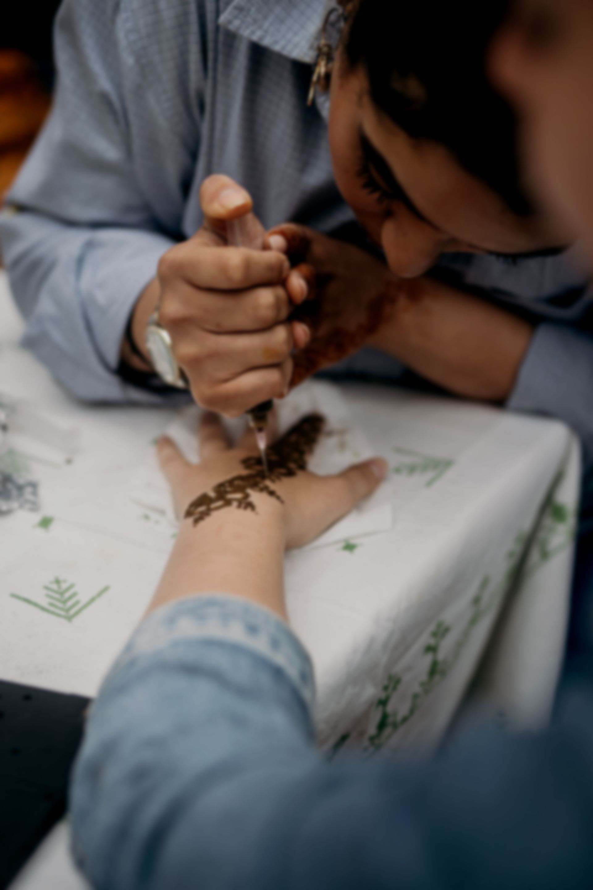 Aya brengt henna aan op de hand van een vrouw