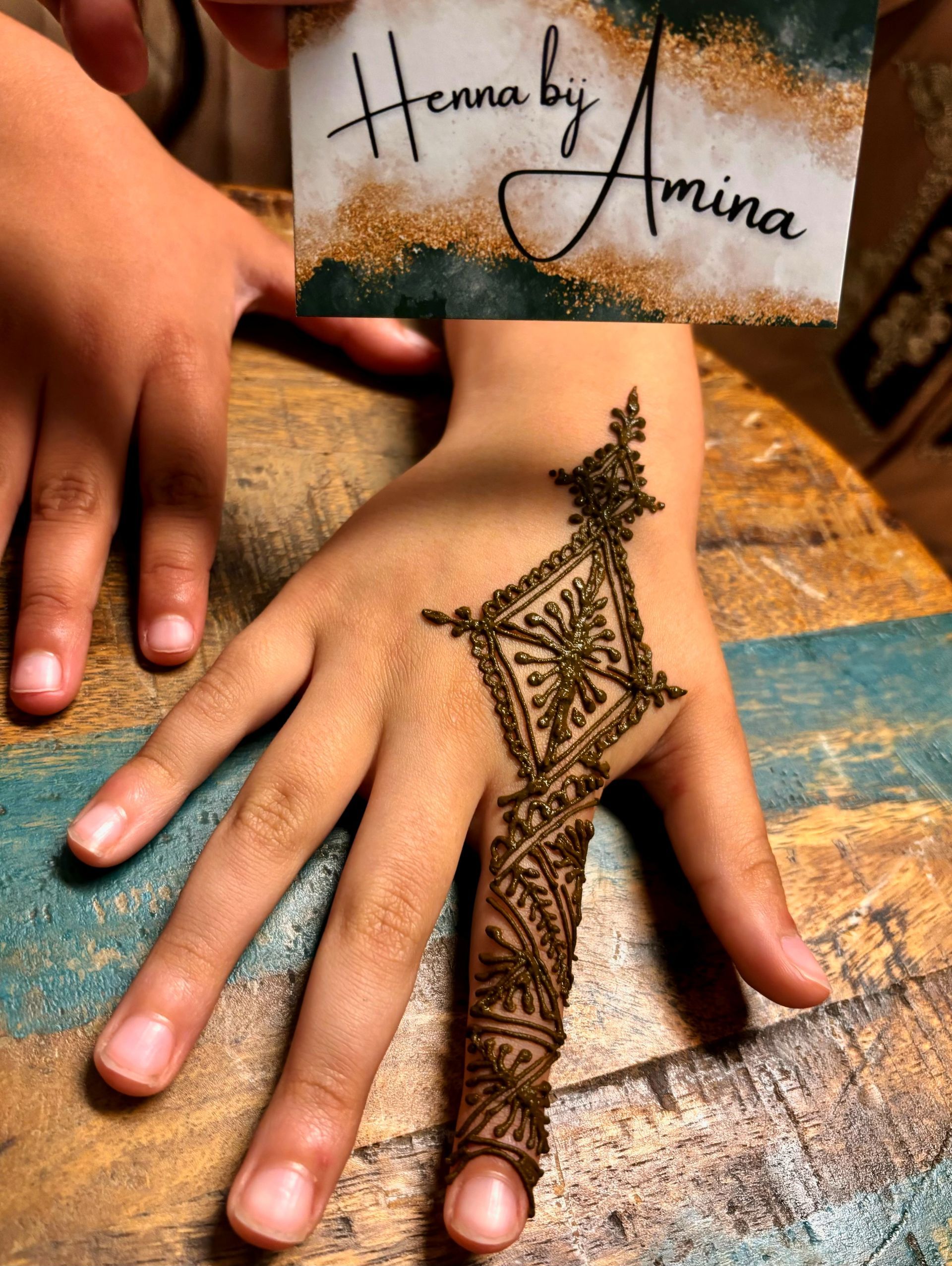 Hand met henna-ontwerp en visitekaartje met de tekst 