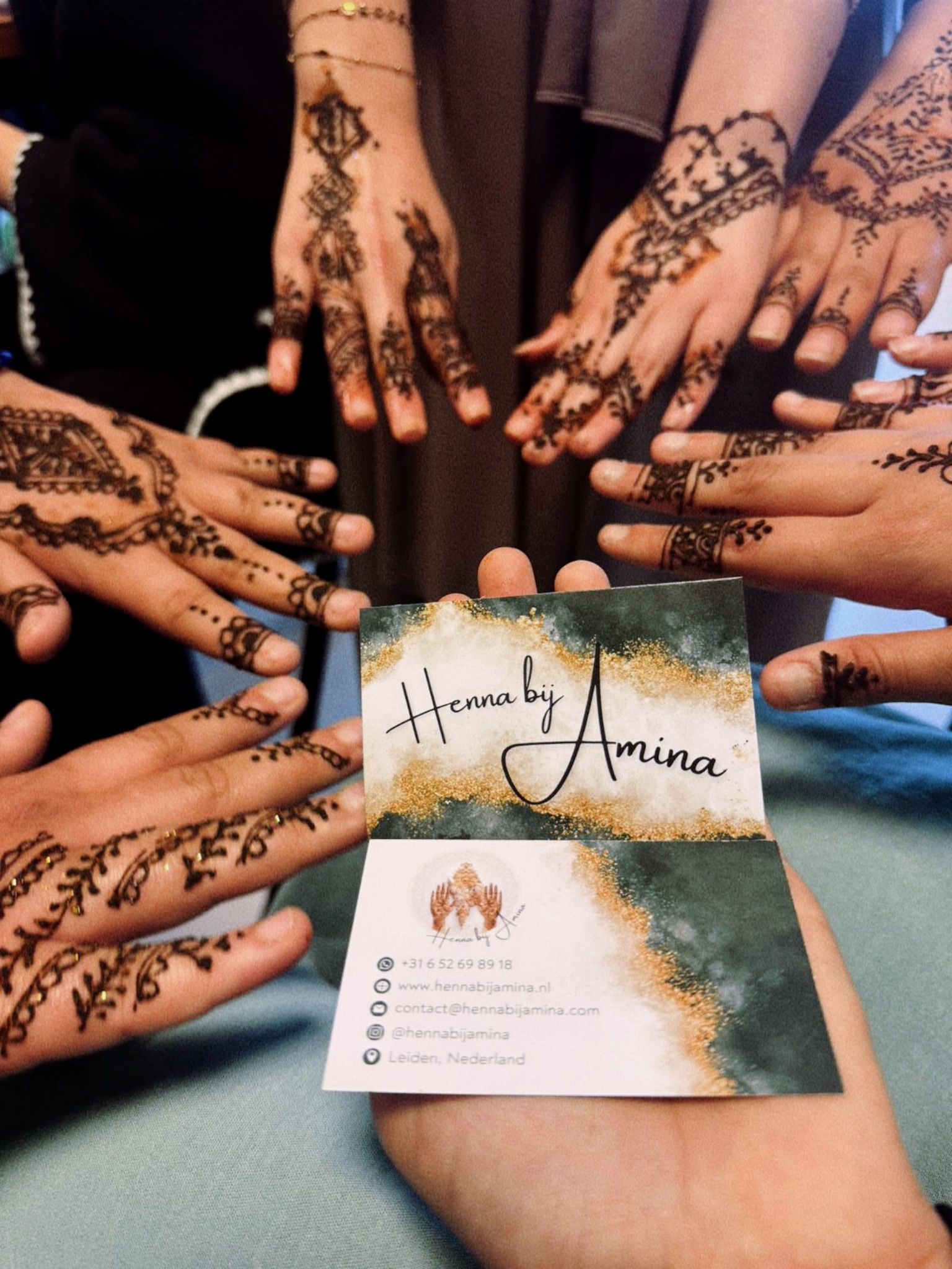 Handen met henna-ontwerpen rond een visitekaartje, 