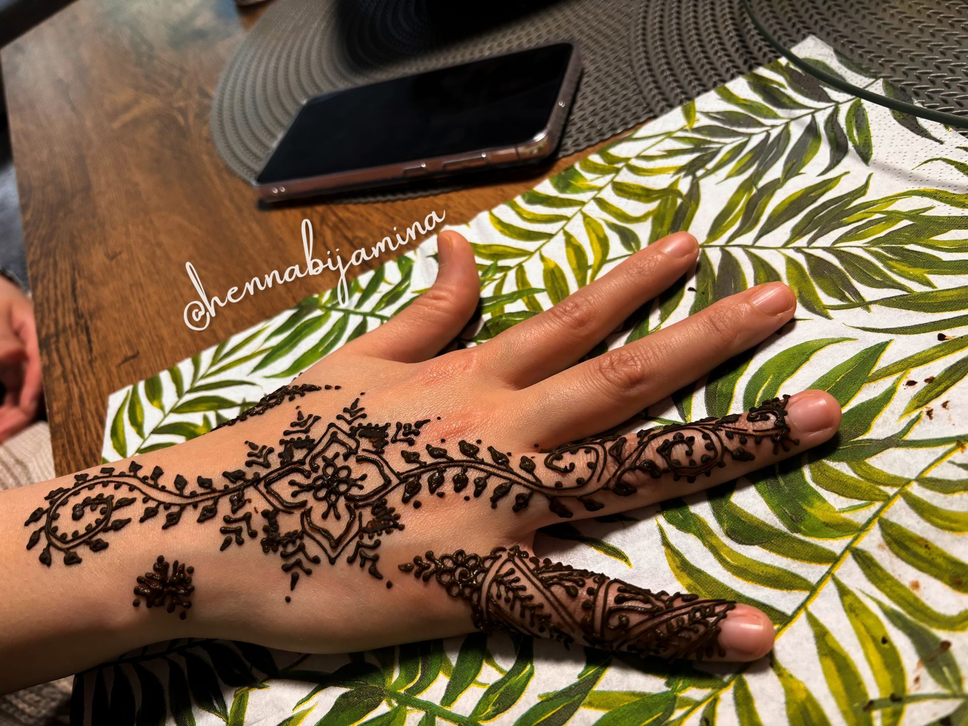 Met de hand versierd met henna, met bloemen- en geometrische patronen, rustend op een doek met bladprint.