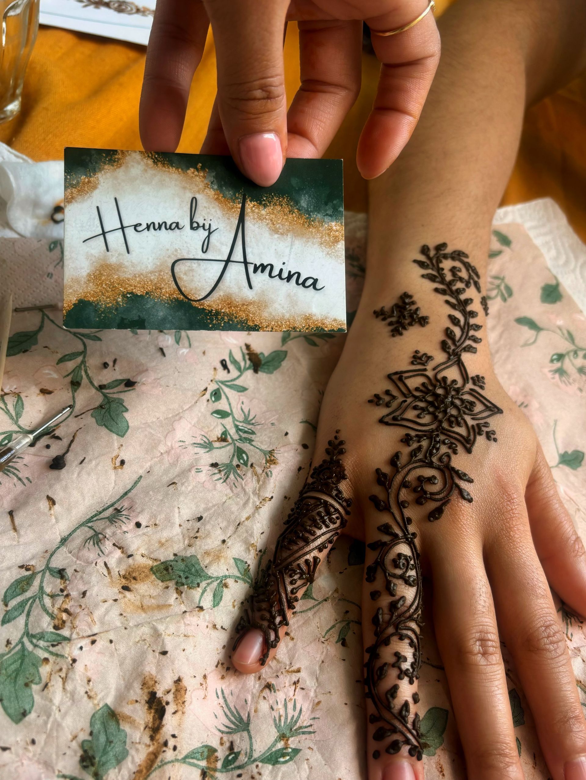Hand met henna-ontwerp en visitekaartje met de tekst 