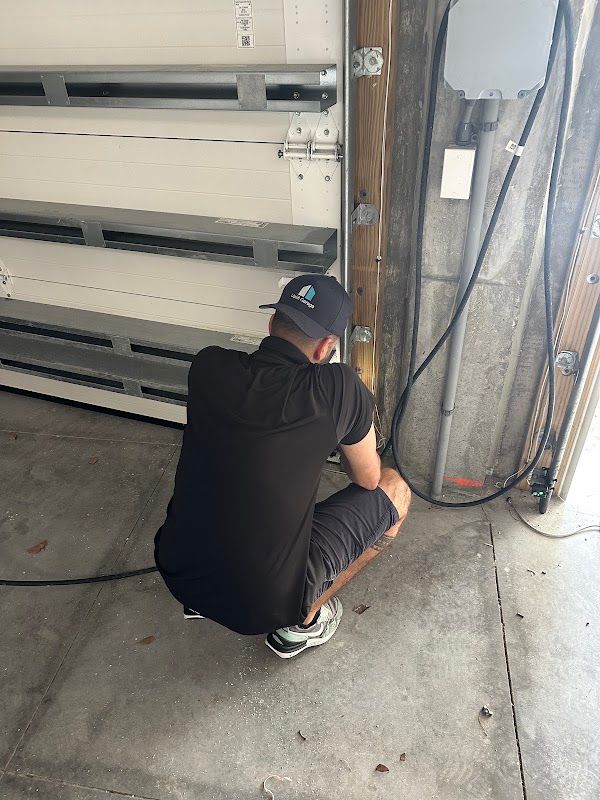 Uplift technician working beside a sectional garage door and track