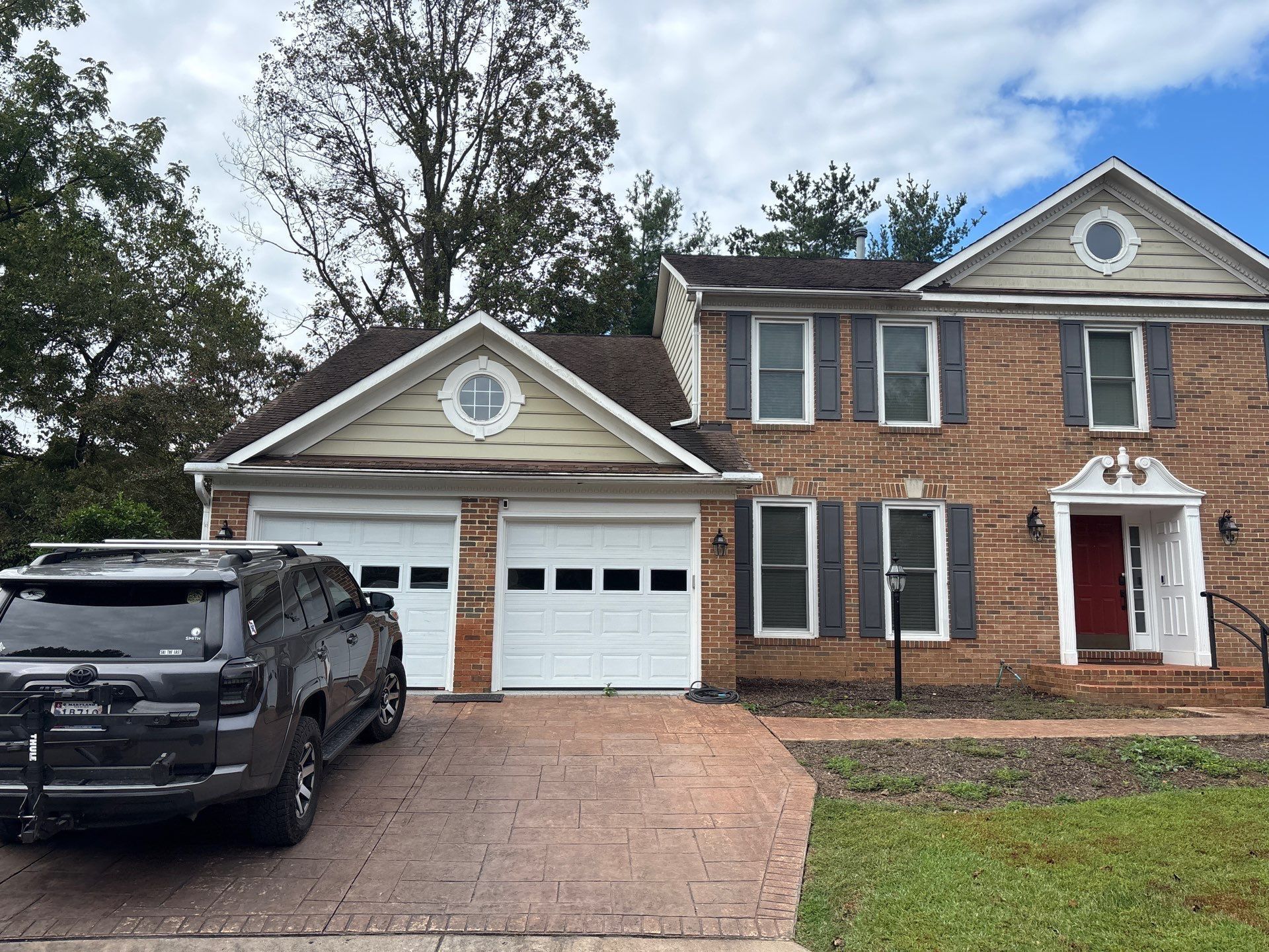 Brick two-story house with attached two-car garage and black SUV parked in the driveway