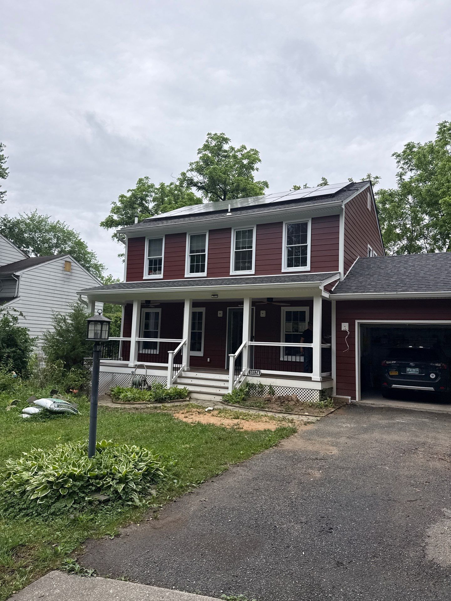 Two-story red house with white trim, front porch, and attached garage on a driveway