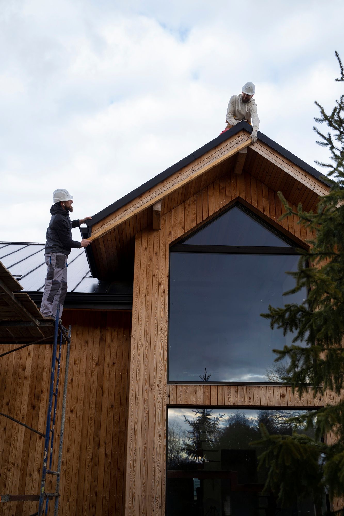 Two men are working on the roof of a wooden building.